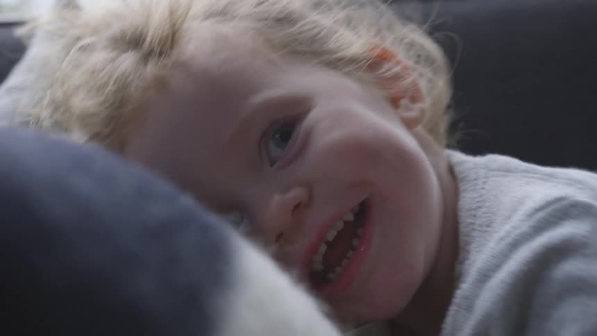 A young girl laughing while on the couch with her father