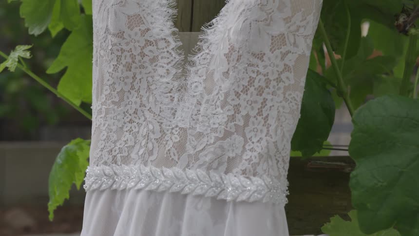 A wedding gown hangs on a post with a grape vine