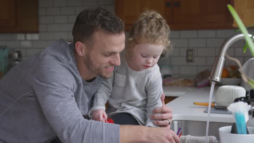 A father kissing his daughter in the kitchen