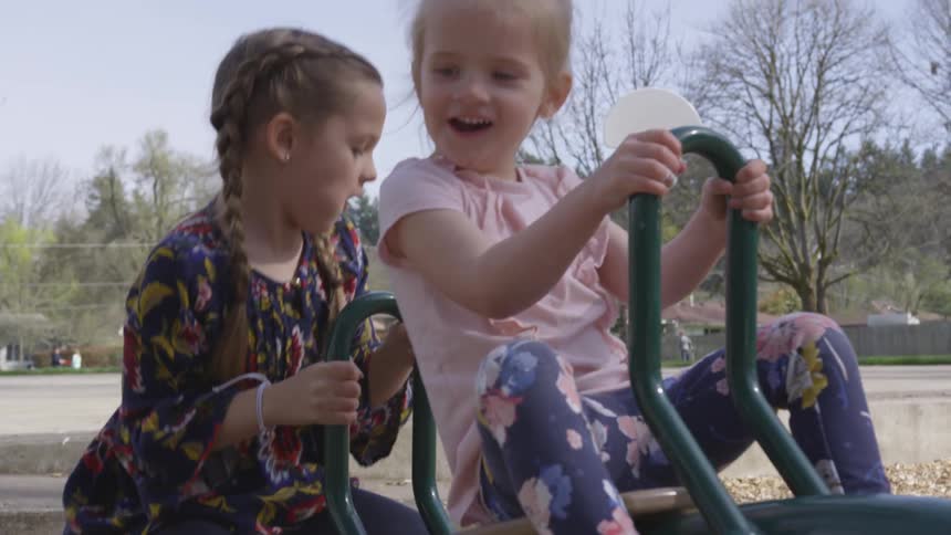 Two children play on a playground seesaw