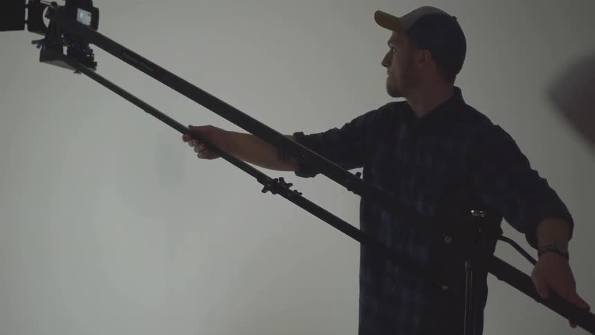 A man is using a long device to lift a camera