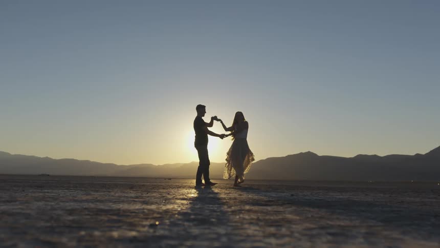 A couple dances together in a sunset