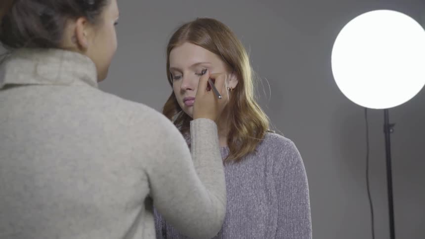 A woman putting makeup on a girl
