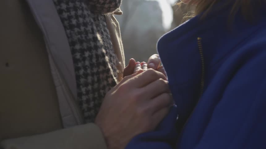 A couple facing each other clasp hands together