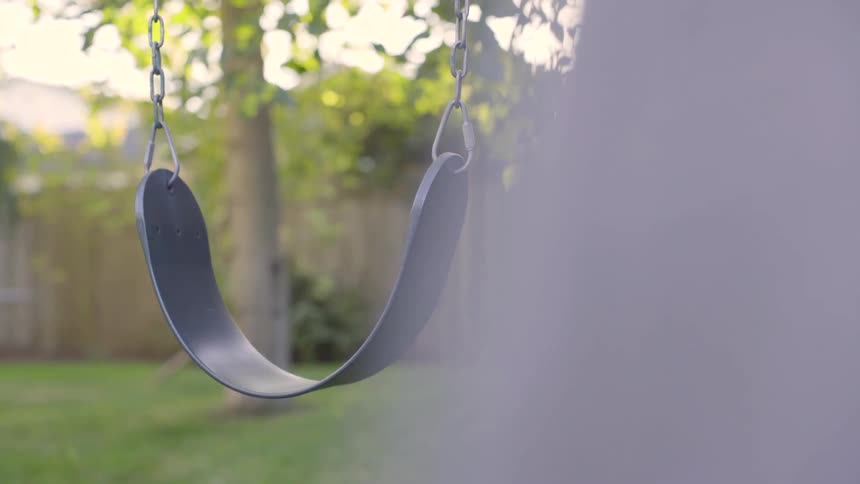 Empty swing with tree in the background under the sun