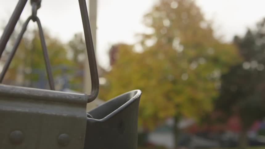 An empty swing gently swings in the wind