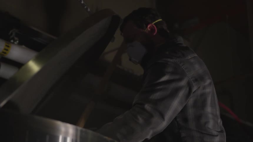 A man stirs a vat inside a brewery