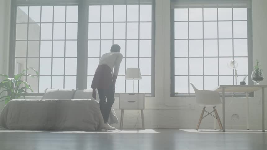 Woman sits on bed in apartment
