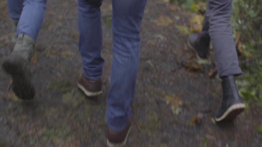 Three people walk along a wet dirt path