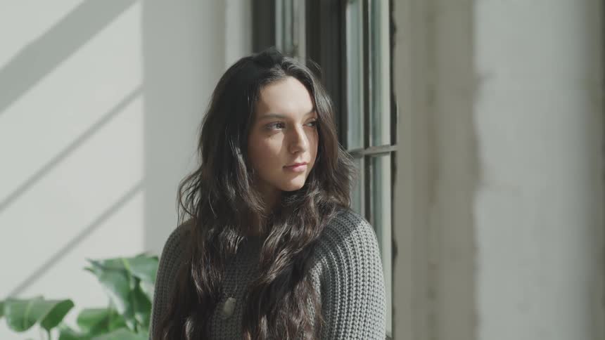 Woman sits looking out window