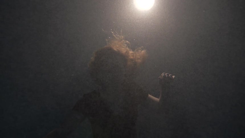 A woman slowly sinks lower in the water