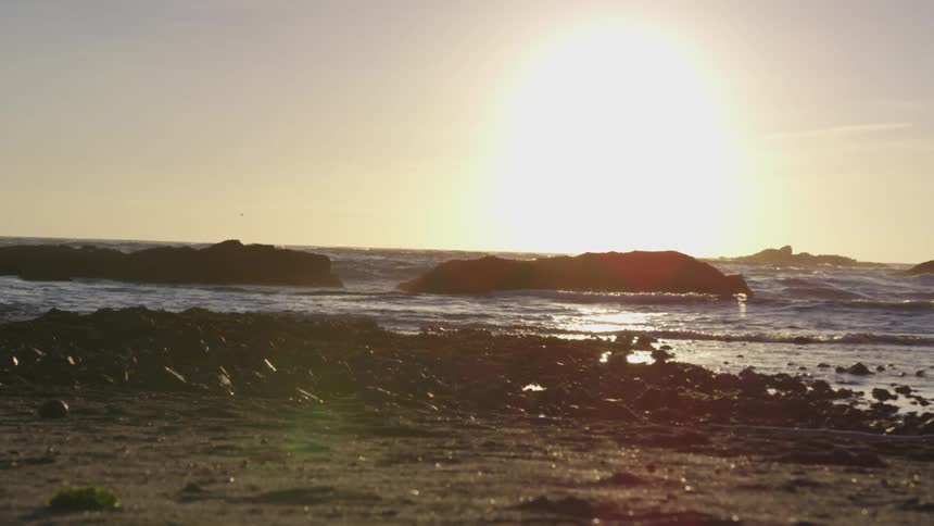 Sun sets over the rocks and the beach