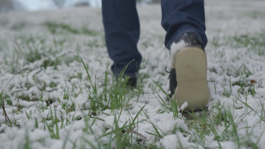 Person walks through snow covered grass during the day
