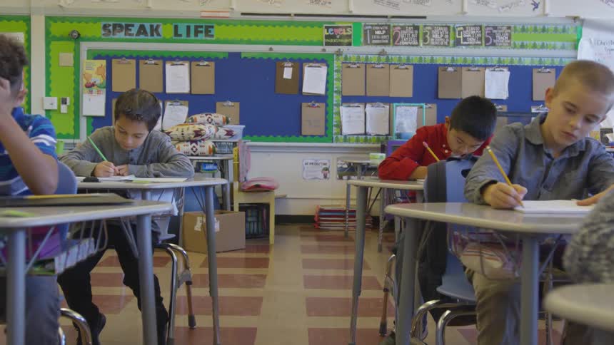 Students uses pencils to do school work in a classroom