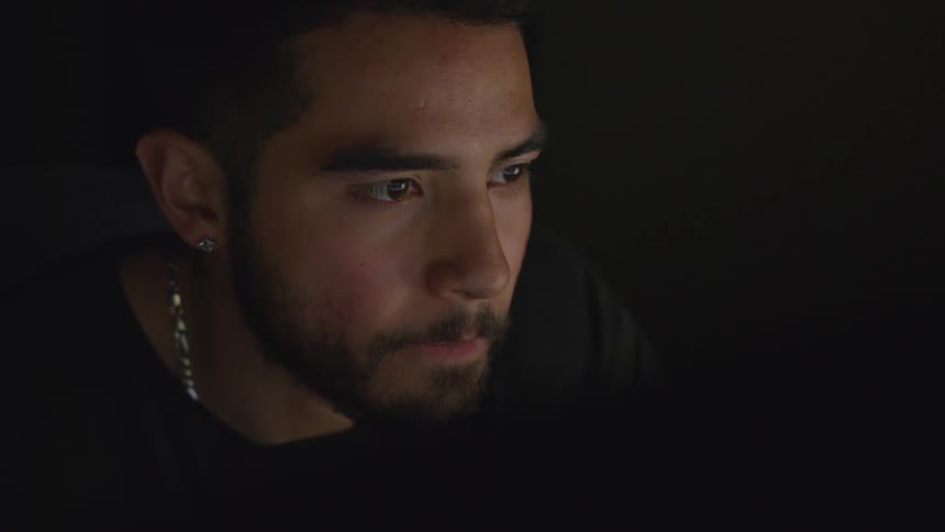 Seated man stares intently at computer