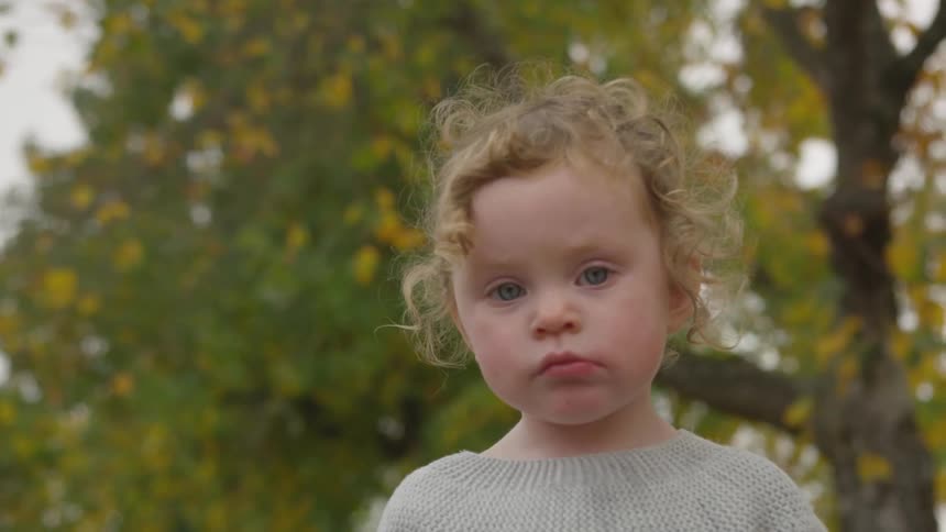 A small child looks towards the ground until she looks around