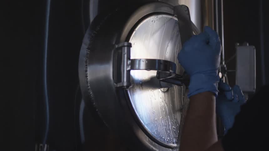 A person wearing blue gloves is turning a lever