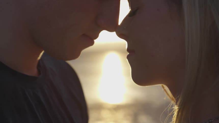 A couple stands nose to nose at sunset