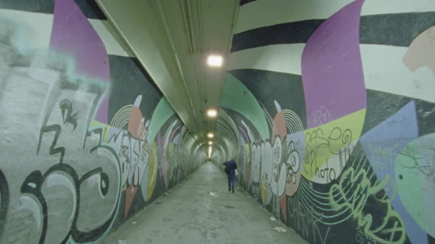 Someone walking through a graffitied tunnel