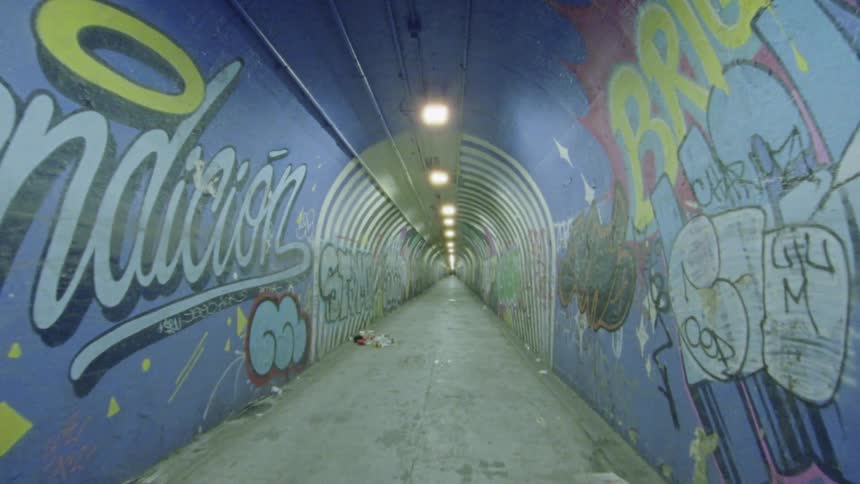 Graffiti covers the walls of a long tunnel