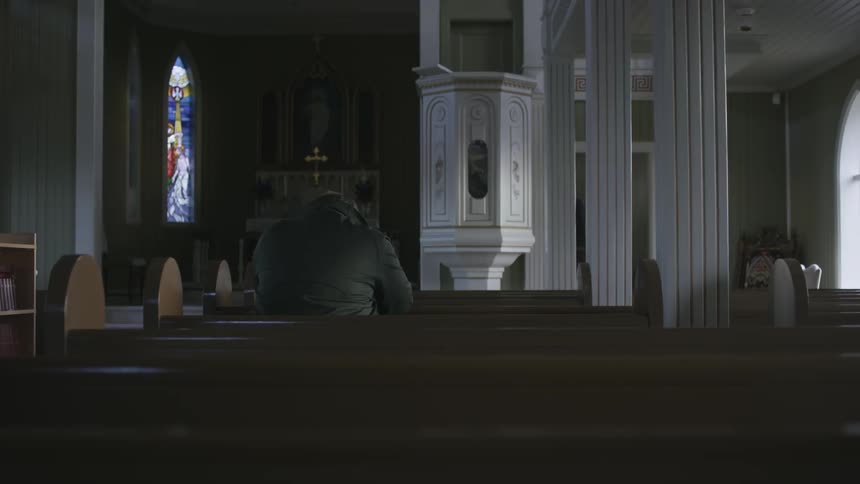A man kneeling in a church pew