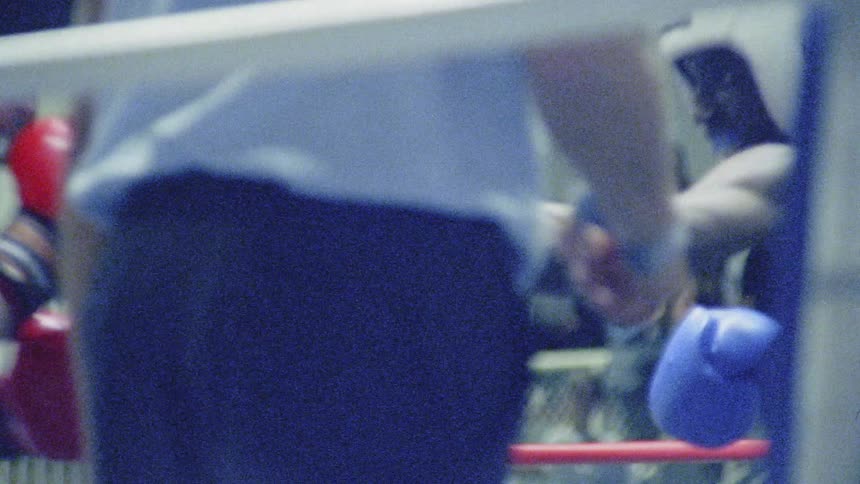 Two boxers fight in an indoor boxing ring