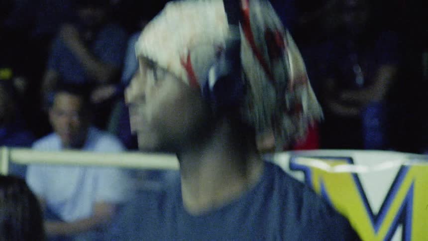 A man wearing headphones jumps and stretches in front of a crowd behind him