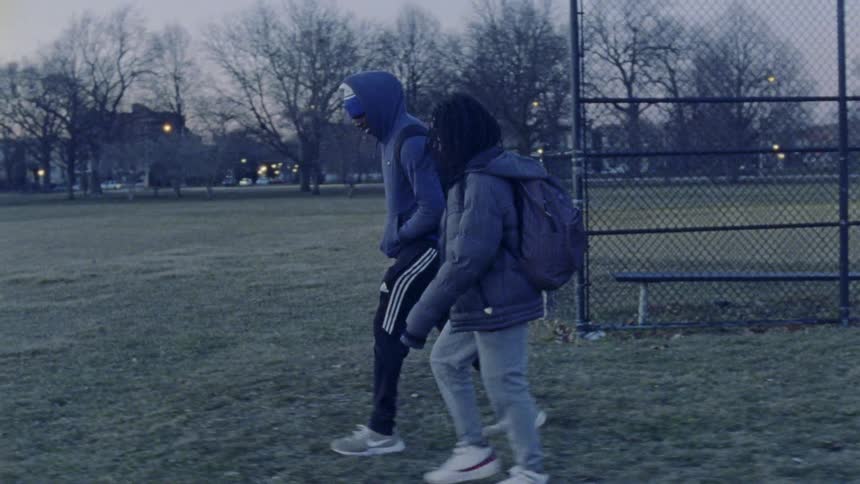 Two children walking across a sport field