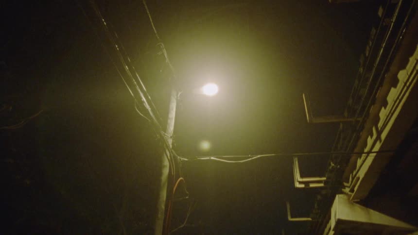 An urban street during night with power lines and a bright street light
