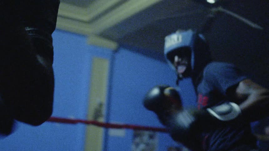 Lights flash while two boxers fight in a boxing ring
