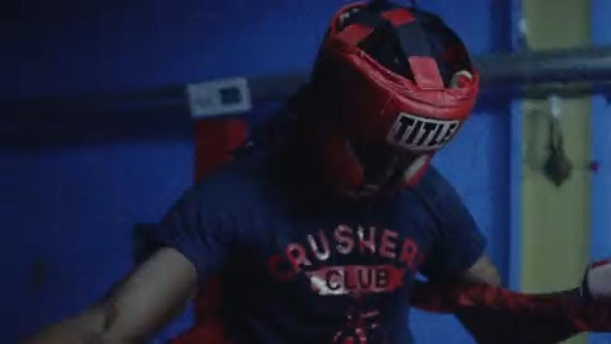 An amateur boxer standing in a ring under a blinking light