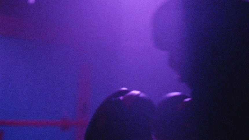 A boxer punching the air in a ring under flashing lights