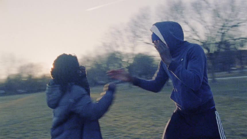 Two people practice boxing on the field