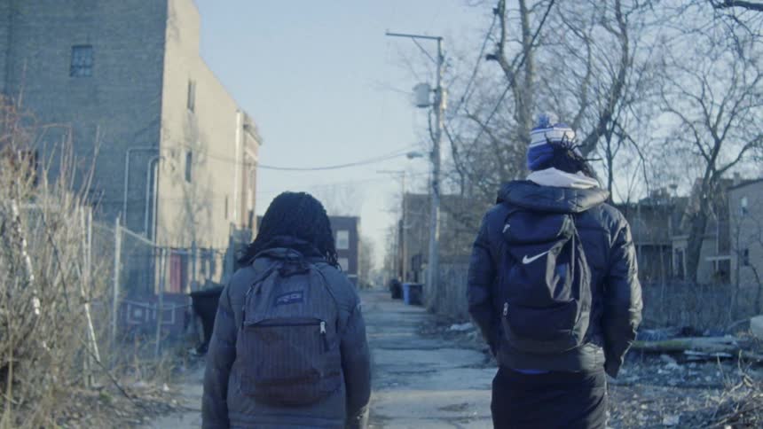Two kids walk down a city alley