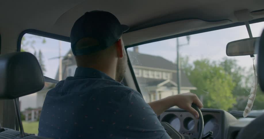 A man is driving past homes in town
