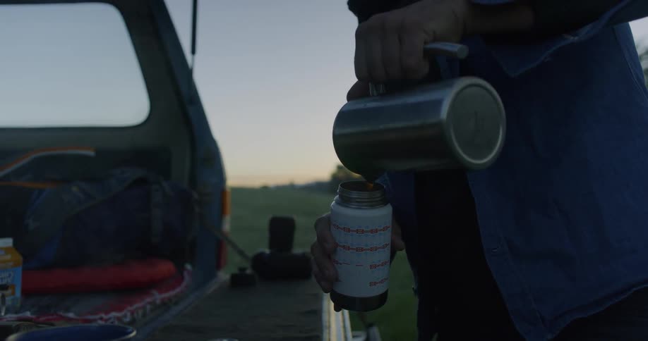 A man pours a hot brew from one flask into another