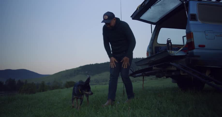 A man and dog are outside at dusk
