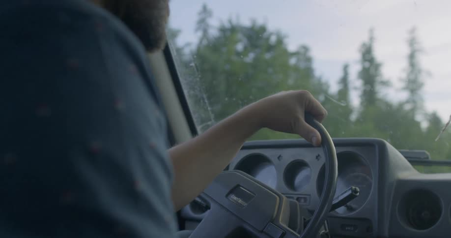 A man is driving his vehicle past a forest