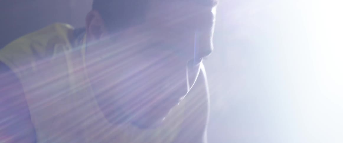 A man leaning over with light shining down on him