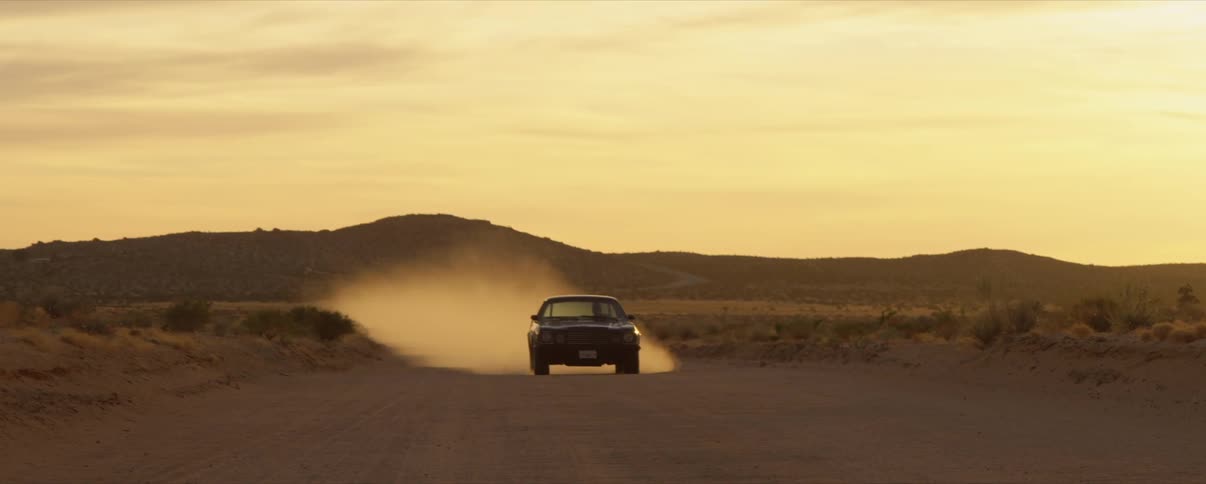 Car drives in desert towards the camera