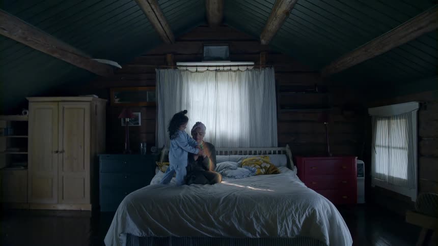 A old woman sits on a bed as she plays with a child