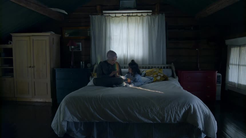 Woman and child sit on a bed as they read a book