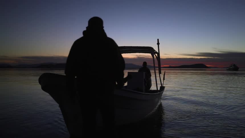 People walk towards boat at sunset