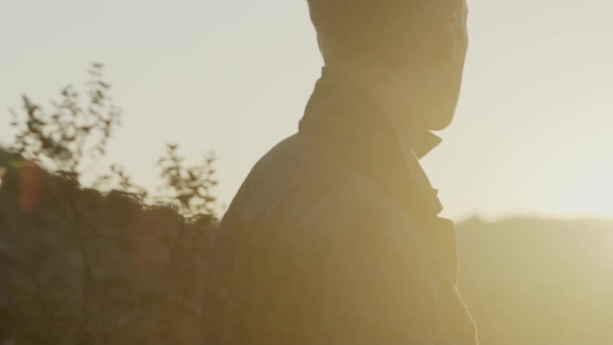 A young man looks towards the horizon at sunset as he walks along a path