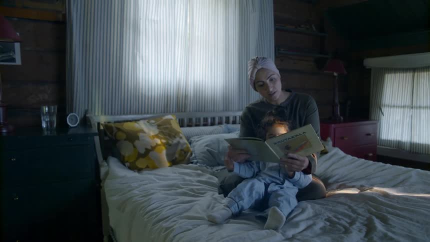 Woman and child are reading a book indoors