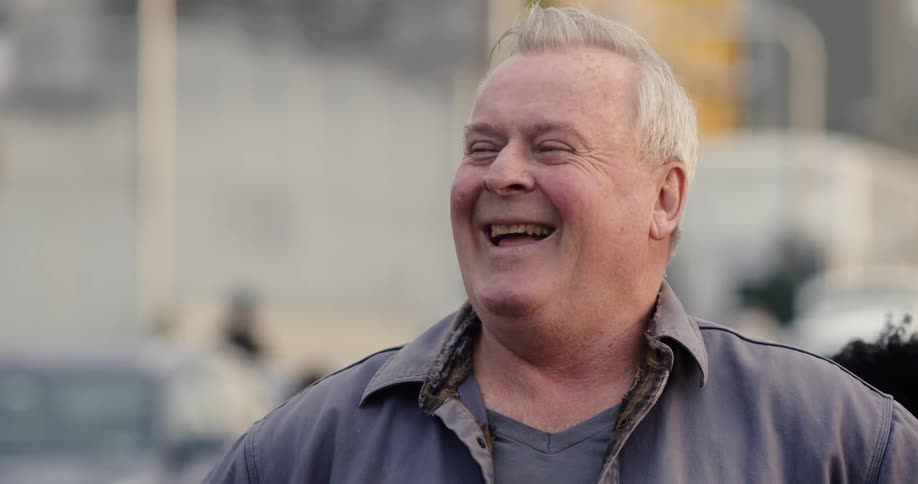 A man is laughing outside on a sunny day
