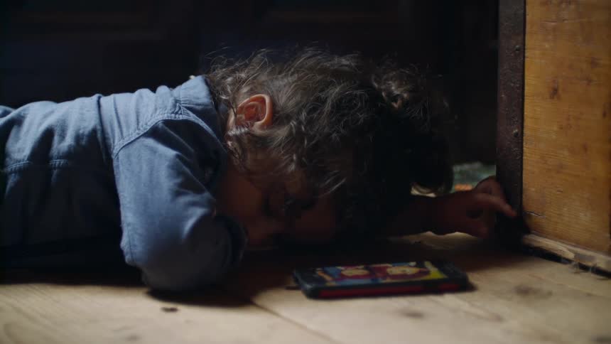 Young boy lays on the floor with a cell phone nearby