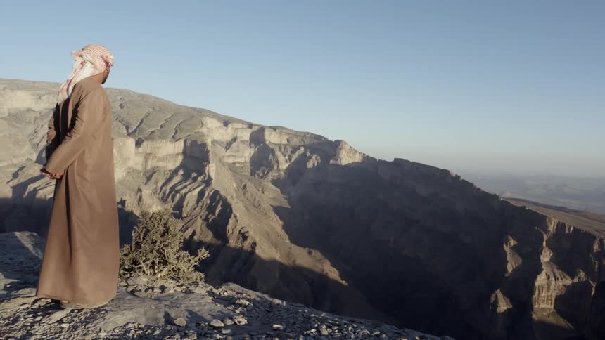 A tall person standing on a large cliff