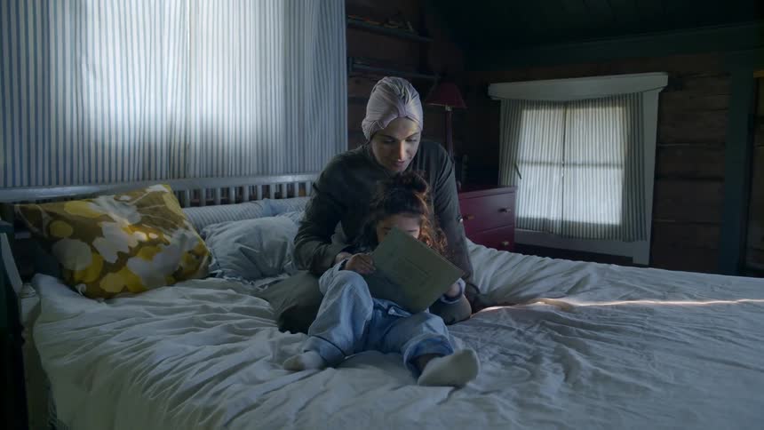 A woman and child read a book together in bed