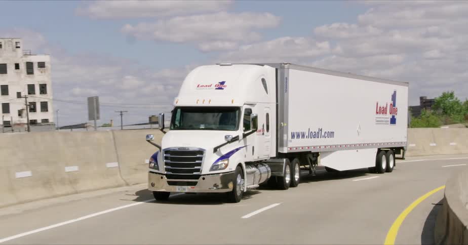 A white semi driving on a ramp of the interstate